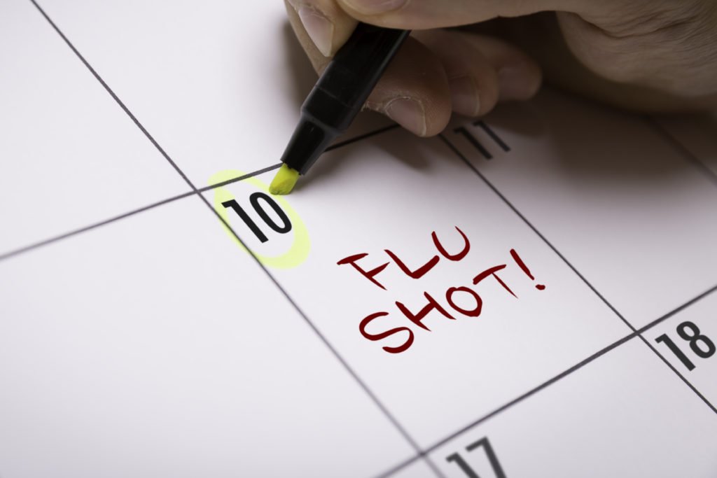 A man marks a flu shot reminder on a calendar