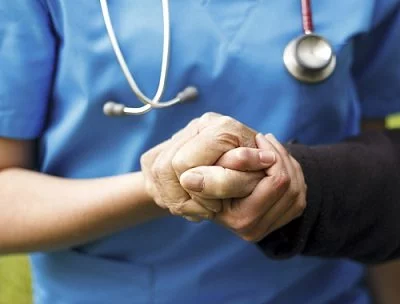 A physician holds a patient's hand