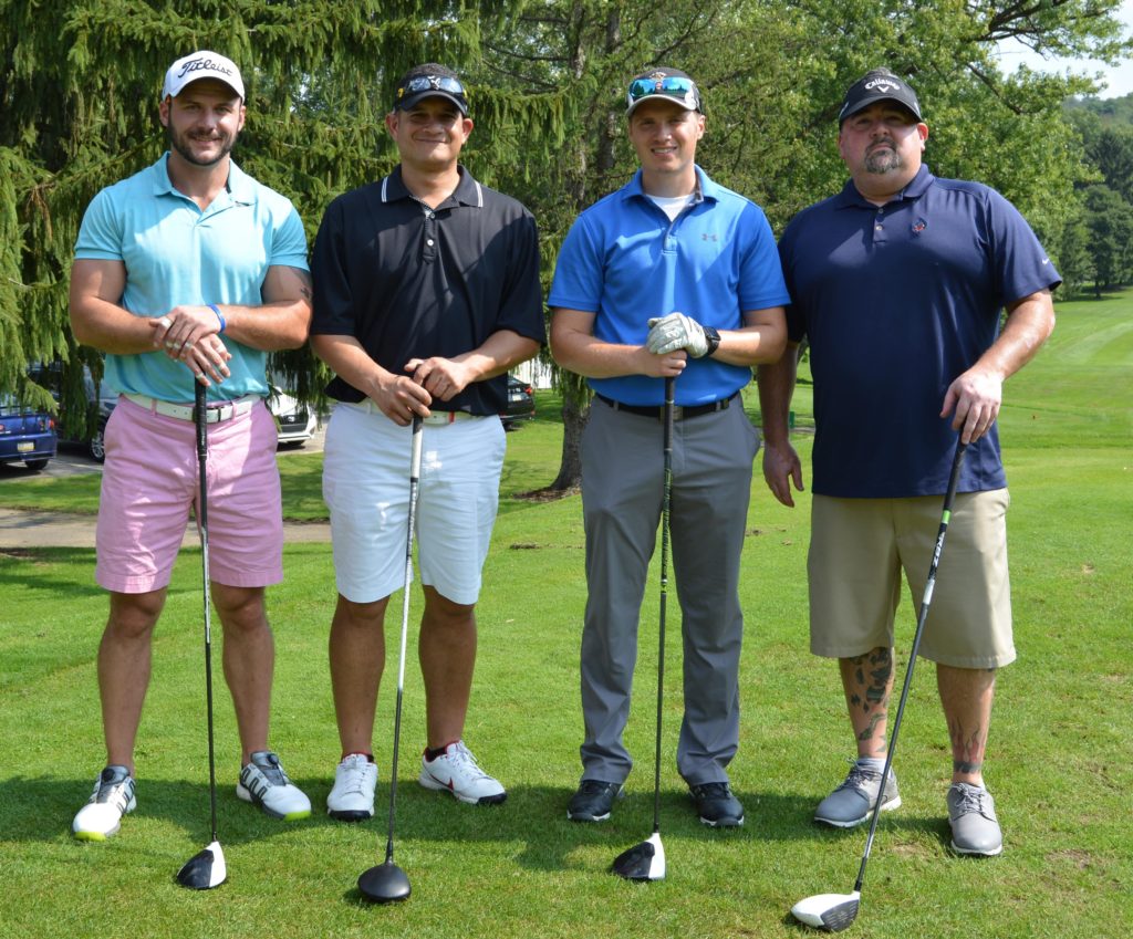Four golfers pose on a course