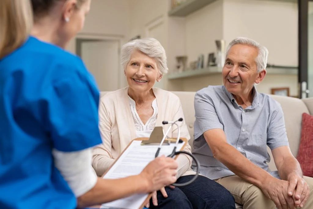 A nurse talks with a couple during a home care visit