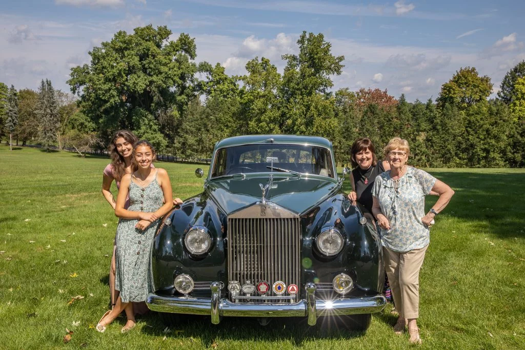 Four women pose with a classic automobile